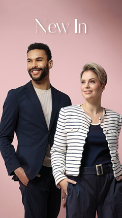 Ein Mann und eine Frau stehen vor einem rosa Hintergrund. Der Mann trägt einen marineblauen Blazer über einem beigen Hemd, während die Frau eine schwarz-weiß gestreifte Jacke trägt. Beide lächeln und blicken in die Ferne. Oben steht der Schriftzug „New In“.